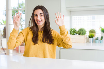 Poster - Beautiful young woman wearing yellow sweater showing and pointing up with fingers number nine while smiling confident and happy.