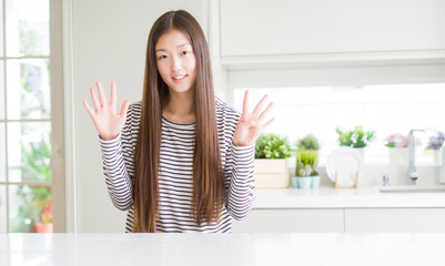 Poster - Beautiful Asian woman wearing stripes sweater showing and pointing up with fingers number nine while smiling confident and happy.