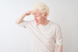 © Krakenimages.com - Young albino blond man wearing casual t-shirt standing over isolated white background very happy and smiling looking far away with hand over head. Searching concept.