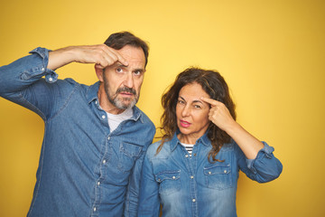 Sticker - Beautiful middle age couple together standing over isolated yellow background pointing unhappy to pimple on forehead, ugly infection of blackhead. Acne and skin problem