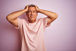 © Krakenimages.com - Handsome middle age man wearing t-shirt standing over isolated pink background suffering from headache desperate and stressed because pain and migraine. Hands on head.