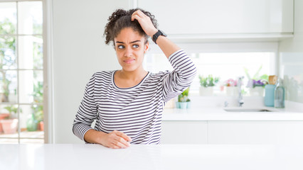 Poster - Beautiful african american woman with afro hair wearing casual striped sweater confuse and wondering about question. Uncertain with doubt, thinking with hand on head. Pensive concept.