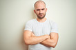 © Krakenimages.com - Young bald man with beard wearing casual white t-shirt over isolated background skeptic and nervous, disapproving expression on face with crossed arms. Negative person.