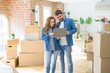 © Krakenimages.com - Young couple using computer laptop standing on a room around cardboard boxes, happy for moving to a new apartment