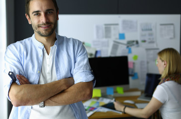 Poster - Portrait of young designer in front of laptop and computer while working. Assistant using her mobile at background.