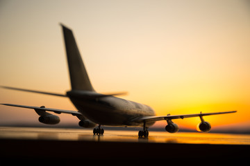 Artwork decoration. White passenger plane ready to taking off from airport runway. Silhouette of Aircraft during sunset time.