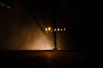 Low key image of jewish holiday Hanukkah background with menorah on dark toned foggy background