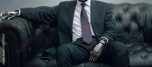 Cuadros en Lienzo Robot businessman sitting on leather sofa, artificial intelligence conceptual de