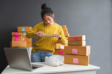 Young women taking photo to shoes with cell telephone or smartphone digital camera for post to sell online on the Internet and preparing pack product box. Selling online ideas concept