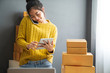 © sutthinon602 - Startup small business SME, Entrepreneur owner using smartphone or tablet taking receive and checking online purchase shopping order to preparing pack product box. Selling online ideas concept