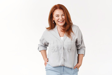 Cheerful charismatic middle-aged redhead beautiful woman smiling toothy happy hold hands pockets pleasant nice conversation feel joyful relaxed after good vacation weekends, white background