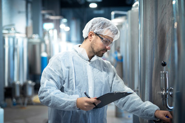 Shot of caucasian male technologist expert operating production machine in food factory and doing quality control.