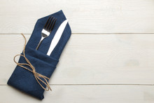 Table Setting. Cutlery. Fork, Knife In A Blue Napkin On A White Wooden Table. Top View
