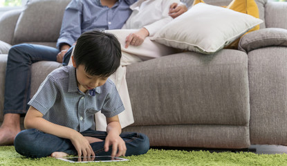 Wall Mural - Boy using tablet in living room and parent watch tv. family and home concept