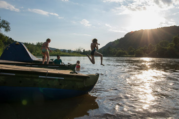 Children jump from a catamaran into the river.