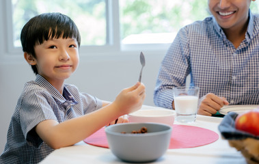 Wall Mural - The boy is having breakfast with his family at home.