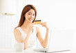 © Tom Wang - Young woman showing credit card and using laptop