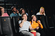 © alfa27 - funny young people talking by phone and laughing while sitting at the cinema Young man enjoying new film with friends in cinema. entertainment and fun.
