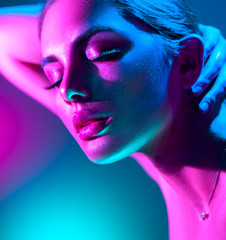 Wall Mural - Fashion model woman in colorful bright neon lights posing in studio. Portrait of beautiful girl in UV. Art design colorful makeup