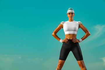 Wall Mural - Sporty and fit young woman athlete relaxed after yoga training on the sky background. The concept of a healthy lifestyle and sport. Individual sports recreation.