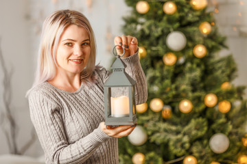 Wall Mural - Happy young lady by the fireplace near the Christmas tree. New year concept.