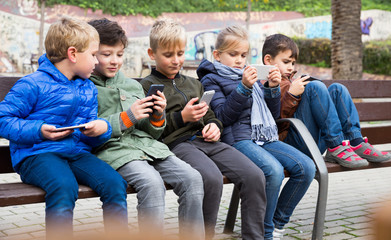  Kids playing with smartphones on bench