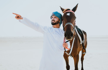 Wall Mural - Arabian man with traditional clothes riding his horse