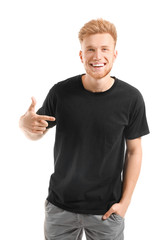 Wall Mural - Man pointing at his t-shirt against white background