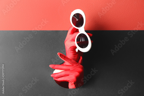 Fotomural Female hands holding stylish sunglasses through hole in paper