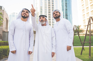 Wall Mural - Businessmen in Dubai speaking about business. Local people with traditional clothes