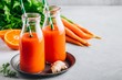 © NBLX - Fresh carrot, ginger and orange drink in glass bottles on a gray stone background