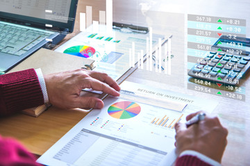 Wall Mural - Businessman on virtual reality graphics is deeply reviewing a financial report for a return on investment or investment risk analysis.