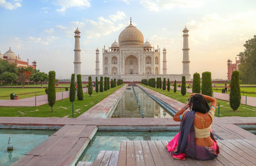 Fototapete - Taj Mahal Agra at sunrise with female tourist clicking photographs of the historic monument