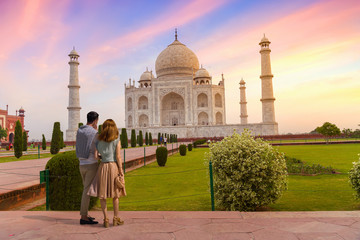 Fototapete - Taj Mahal white marble mausoleum at sunset with view of tourist couple enjoying the sunrise view at Agra, India