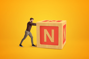 Fototapete - Man wearing casual clothes pushing big alphabet toy block on yellow background.