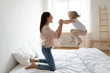 © fizkes - Little daughter frolics jumping on bed holding mothers hands