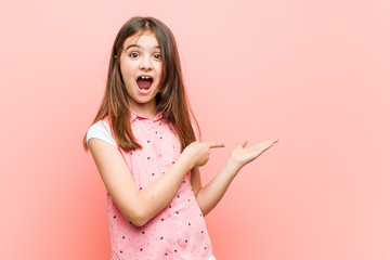 Cute little girl excited holding a copy space on palm.