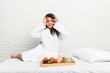 © Asier - Young curvy woman taking a breakfast on the bed keeping eyes opened to find a success opportunity.