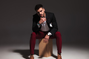 Wall Mural - pensive young attractive man sitting on wood box