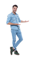 Wall Mural - casual young man wearing denim and presenting to side