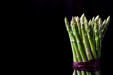 Bunch of raw green asparagus against black background