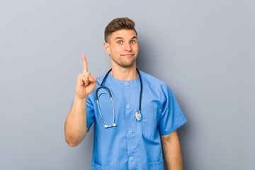 Wall Mural - Young nurse man showing number one with finger.