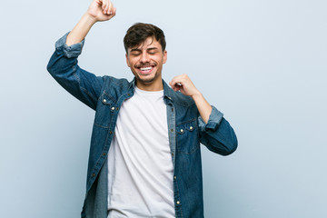 Young hispanic cool man celebrating a special day, jumps and raise arms with energy.