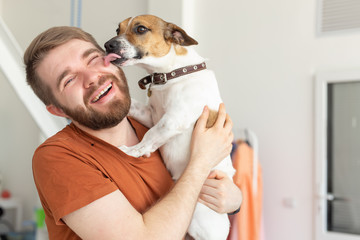 Animal, pet and people concept - Attractive cheerful man in t-shirt holds favourite pet