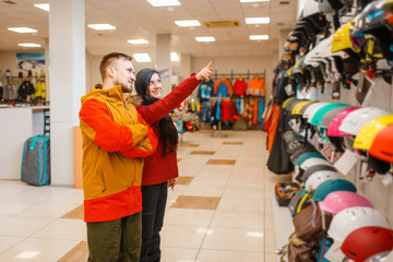 Wall Mural - Young couple choosing helmets, sports shop