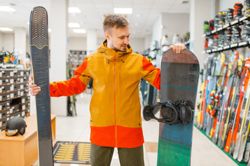 Wall Mural - Man choosing downhill ski and snowboard, shopping