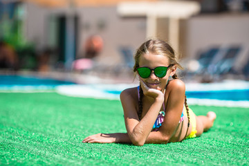 Beautiful little girl having fun near an outdoor pool