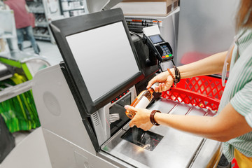 Girl customer scans bottle of wine at the self-service checkout in the grocery supermarket shop