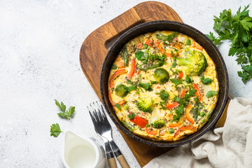 Frittata with vegetables on white stone table.