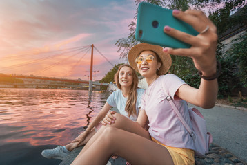 Wall Mural - Two happy girl friends taking selfie photo on a bank of Saone river in Lyon